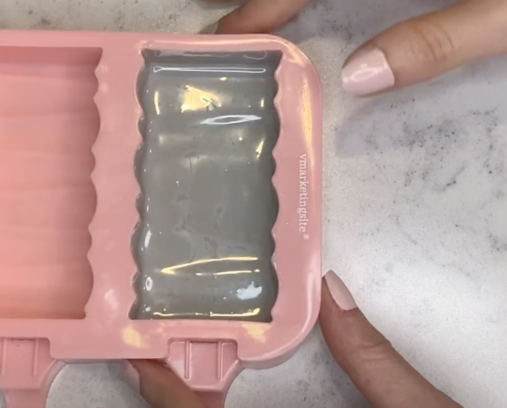 Silicone mold filled with chocolate, excess pooled at the bottom